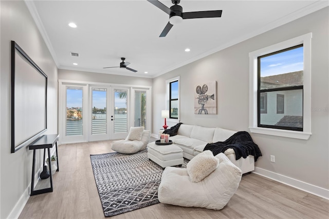 living area with light wood finished floors, baseboards, visible vents, and crown molding