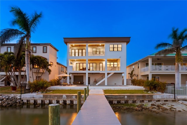 rear view of property with a patio, a balcony, a water view, fence, and stucco siding