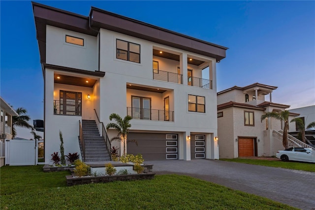 contemporary home with decorative driveway, stairway, a balcony, and stucco siding