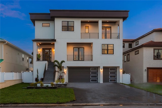 modern home with a garage, stairway, decorative driveway, and stucco siding