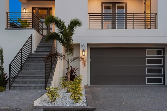 view of front of property with stairs, decorative driveway, and stucco siding