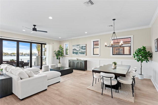 living room featuring crown molding, visible vents, a water view, and light wood finished floors