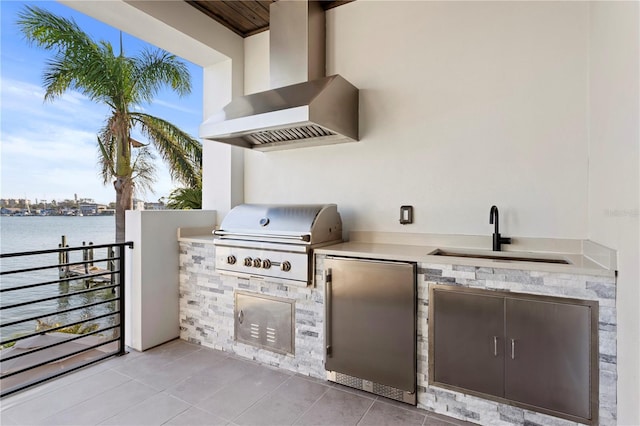 view of patio with area for grilling, an outdoor kitchen, a sink, and a water view