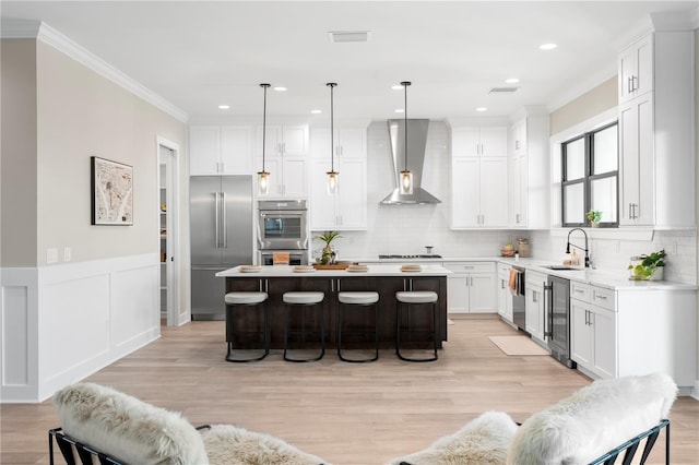 kitchen with hanging light fixtures, wall chimney exhaust hood, light countertops, and a center island