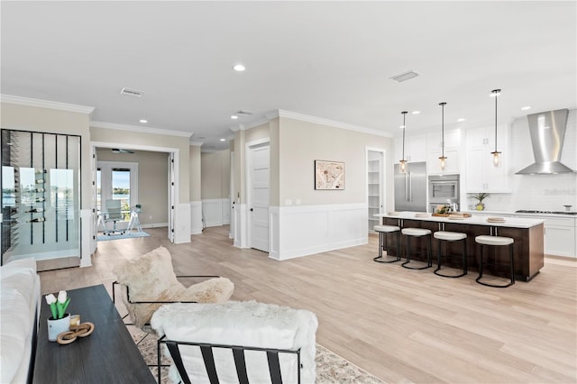 living room featuring light wood-style flooring, visible vents, and crown molding