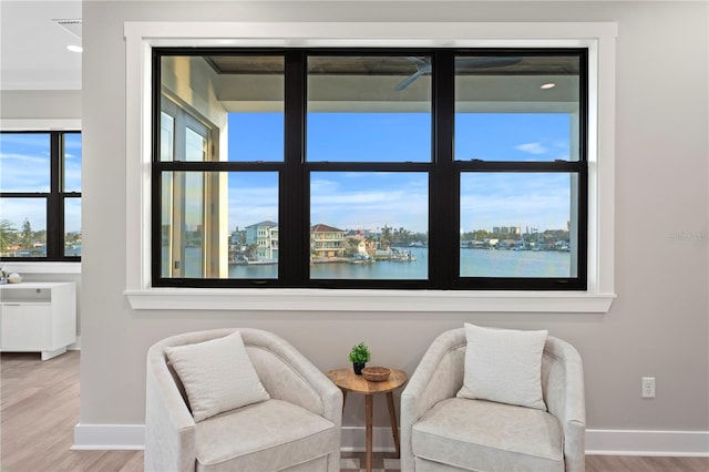 living area featuring a water view, visible vents, baseboards, and wood finished floors