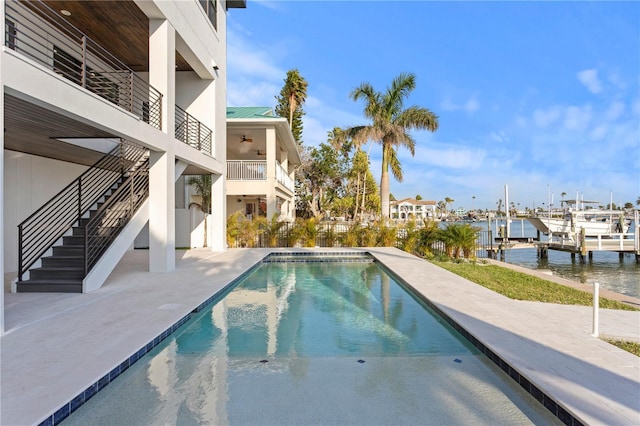 outdoor pool featuring a patio, boat lift, a water view, stairs, and a boat dock