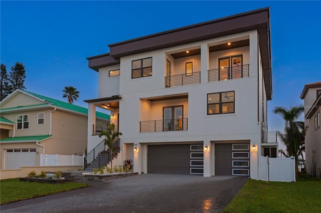 contemporary house featuring driveway, a balcony, an attached garage, and stucco siding