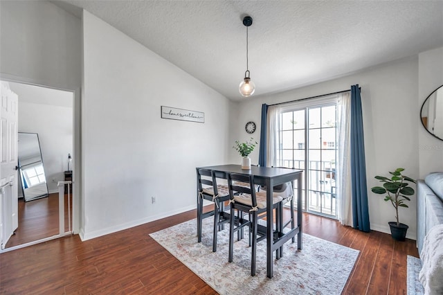 dining room featuring a textured ceiling, lofted ceiling, and dark hardwood / wood-style floors