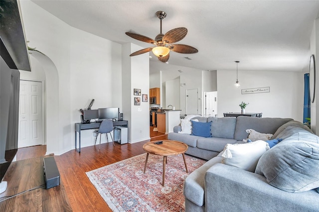 living room featuring vaulted ceiling, ceiling fan, and dark wood-type flooring