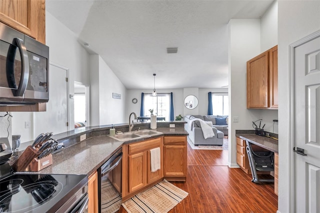 kitchen featuring sink, stainless steel appliances, dark hardwood / wood-style flooring, kitchen peninsula, and decorative light fixtures