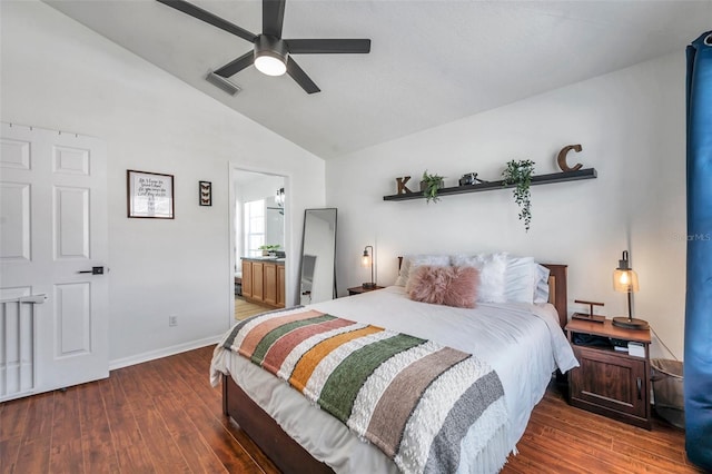 bedroom featuring dark hardwood / wood-style flooring, ensuite bathroom, vaulted ceiling, and ceiling fan