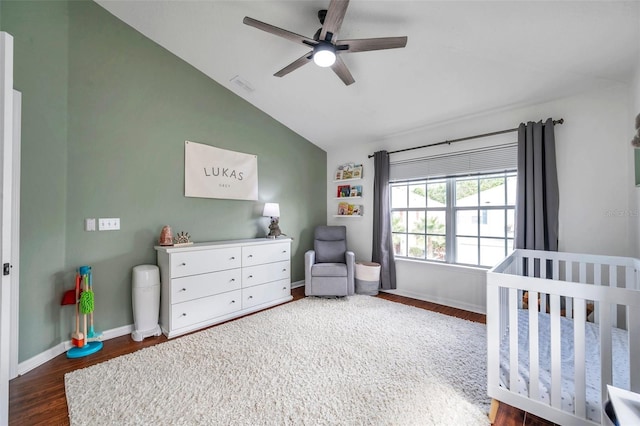 bedroom featuring ceiling fan, dark hardwood / wood-style floors, lofted ceiling, and a nursery area