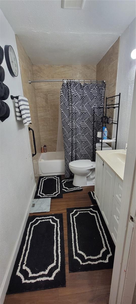 full bathroom with vanity, toilet, wood-type flooring, and shower / tub combo with curtain