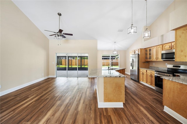 kitchen with a center island with sink, light stone counters, stainless steel appliances, and high vaulted ceiling