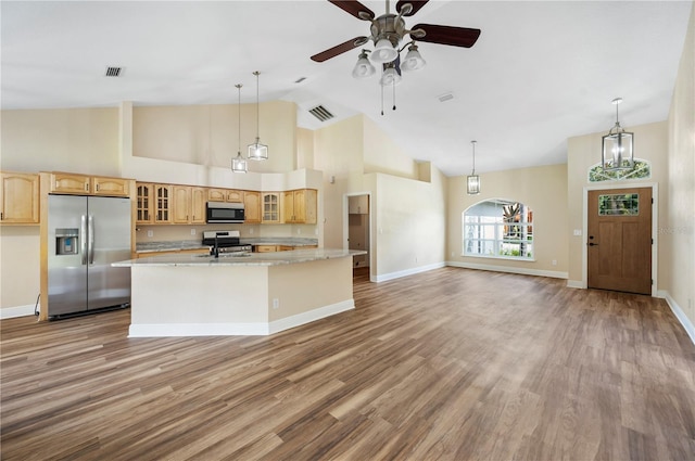 kitchen featuring stainless steel appliances, light hardwood / wood-style flooring, high vaulted ceiling, a kitchen island with sink, and ceiling fan with notable chandelier