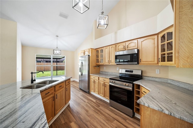 kitchen with light stone counters, sink, stainless steel appliances, and hanging light fixtures