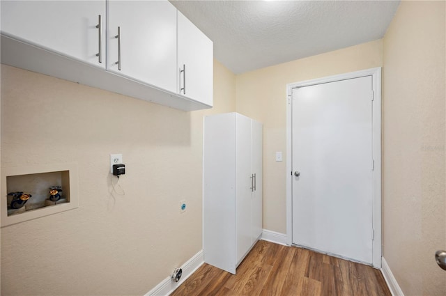 clothes washing area with cabinets, hookup for an electric dryer, hardwood / wood-style floors, hookup for a washing machine, and a textured ceiling