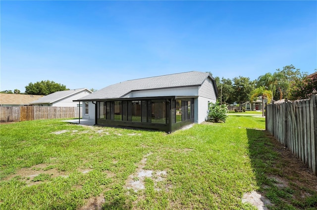 rear view of property featuring a sunroom and a yard