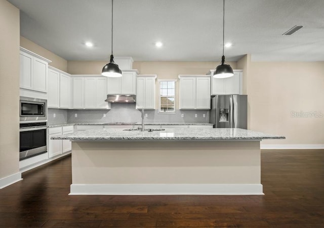 kitchen with a center island with sink, pendant lighting, light stone countertops, and appliances with stainless steel finishes