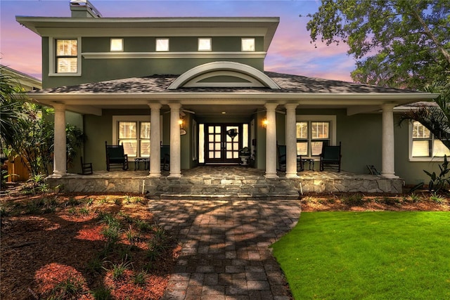 exterior entry at dusk with a porch and a yard