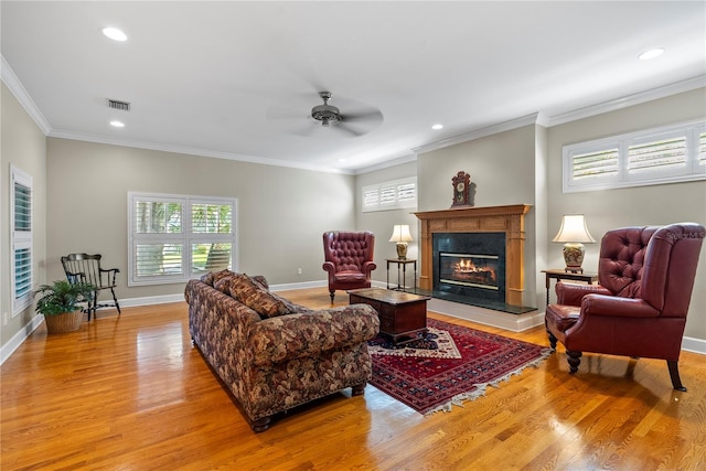 living room featuring crown molding, ceiling fan, light wood-type flooring, and a wealth of natural light