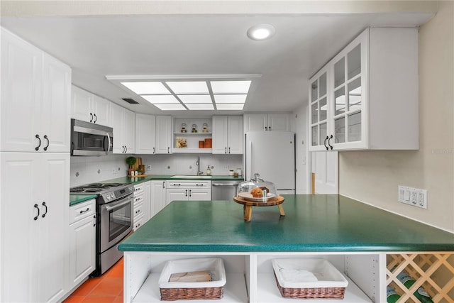 kitchen featuring light tile patterned flooring, appliances with stainless steel finishes, sink, white cabinets, and decorative backsplash