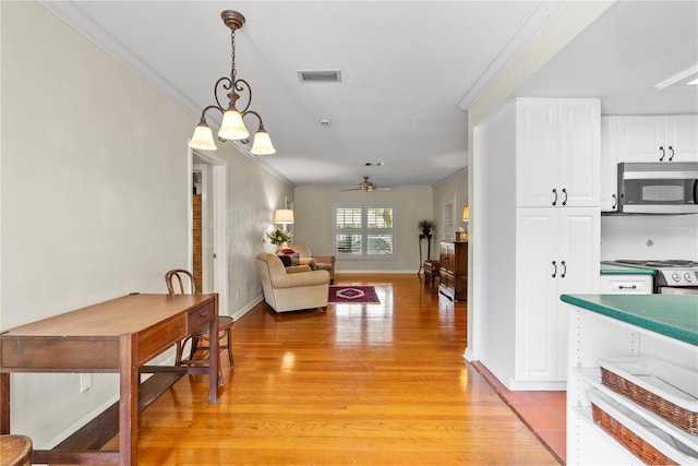 dining space with crown molding, ceiling fan with notable chandelier, and light hardwood / wood-style flooring