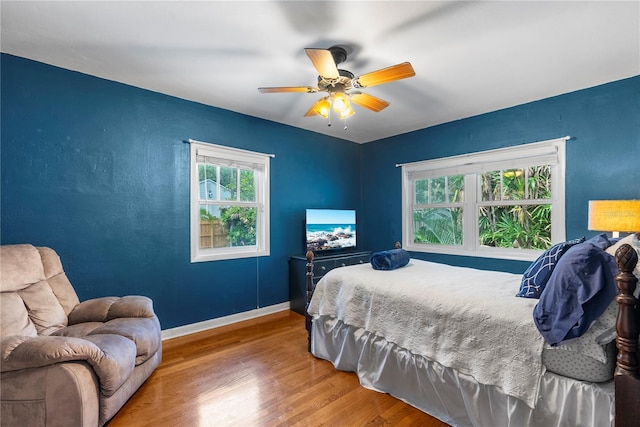 bedroom featuring multiple windows, hardwood / wood-style floors, and ceiling fan