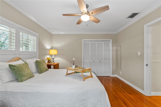 bedroom with dark wood-type flooring, ceiling fan, crown molding, and a closet