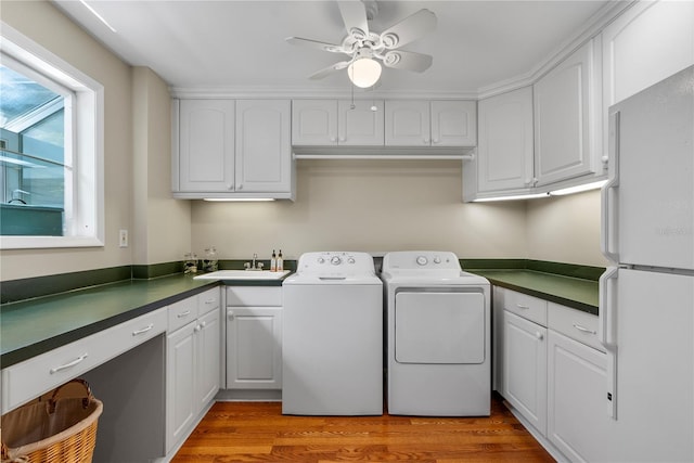 laundry room with sink, cabinets, ceiling fan, washing machine and dryer, and light hardwood / wood-style flooring