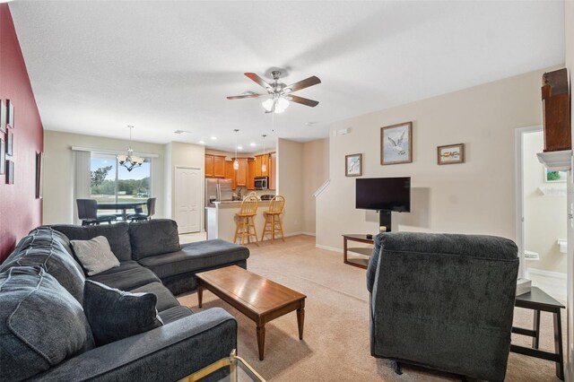 carpeted living room featuring ceiling fan with notable chandelier