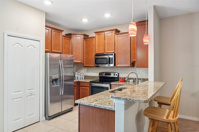 kitchen with pendant lighting, a breakfast bar, kitchen peninsula, sink, and appliances with stainless steel finishes