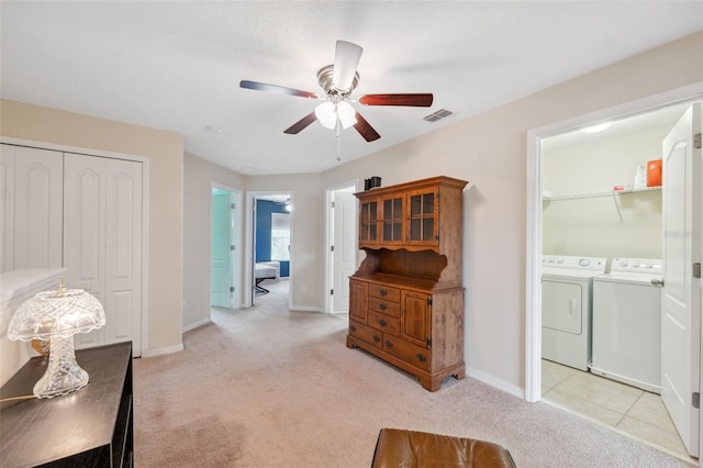 interior space featuring ceiling fan, light colored carpet, and washing machine and dryer