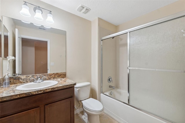 full bathroom featuring toilet, bath / shower combo with glass door, tile patterned floors, a textured ceiling, and vanity