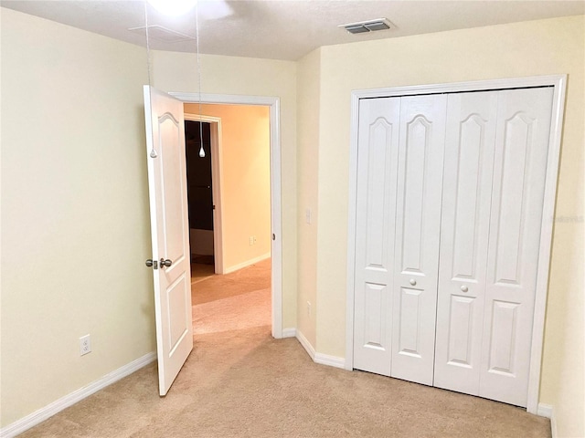 unfurnished bedroom featuring light carpet and a closet