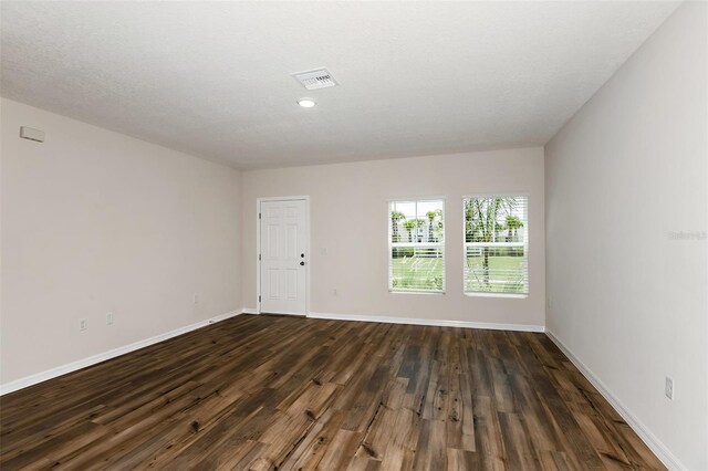 unfurnished room with dark hardwood / wood-style flooring and a textured ceiling