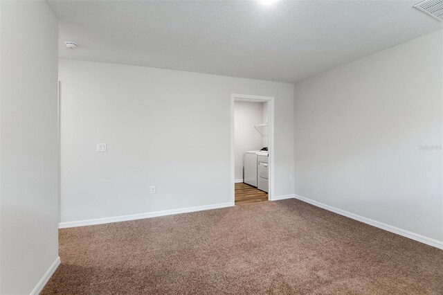 unfurnished room with a textured ceiling, washer and clothes dryer, and carpet flooring