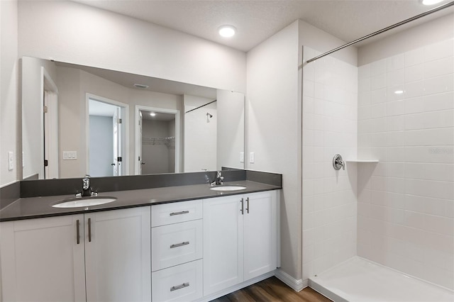 bathroom with vanity, a tile shower, hardwood / wood-style flooring, and a textured ceiling