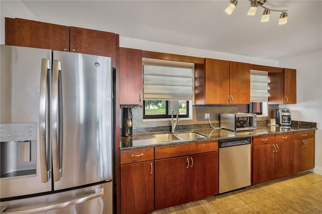 kitchen featuring sink, decorative backsplash, dark stone countertops, light tile patterned flooring, and stainless steel appliances