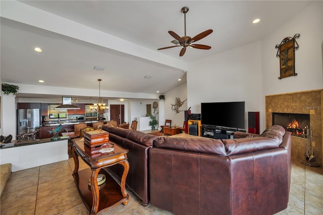 living room featuring vaulted ceiling, a premium fireplace, light tile patterned flooring, and ceiling fan with notable chandelier