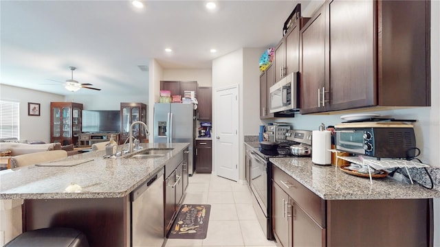 kitchen with light stone countertops, appliances with stainless steel finishes, sink, and an island with sink