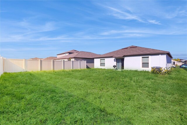 back of property with fence, a lawn, and stucco siding