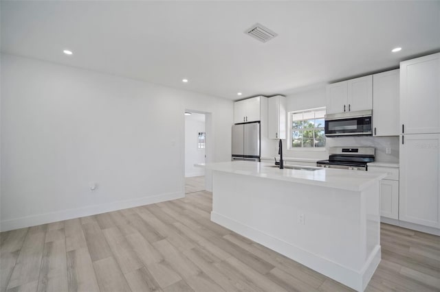 kitchen featuring white cabinets, sink, stainless steel appliances, and a kitchen island with sink