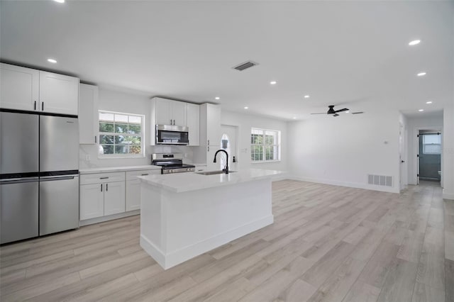 kitchen featuring ceiling fan, sink, stainless steel appliances, a kitchen island with sink, and white cabinets