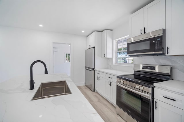 kitchen with white cabinetry, light stone countertops, sink, and appliances with stainless steel finishes