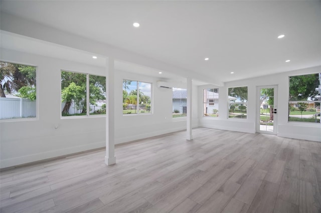 interior space with a wall mounted air conditioner and light wood-type flooring