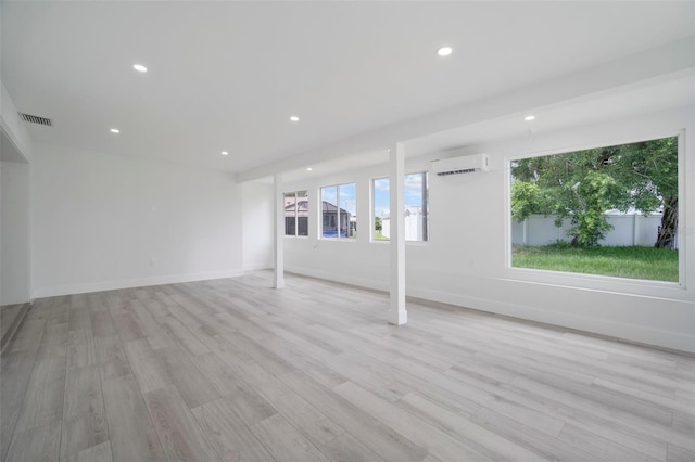 empty room featuring a wall mounted air conditioner and light hardwood / wood-style flooring