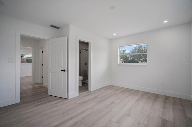 unfurnished bedroom featuring ensuite bath and light hardwood / wood-style floors