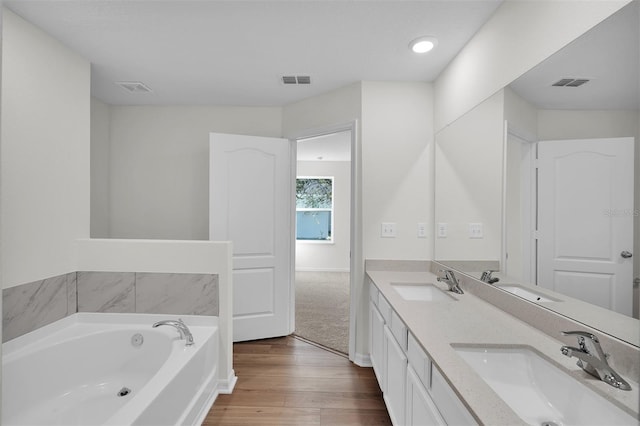 bathroom with a tub to relax in, vanity, and wood-type flooring